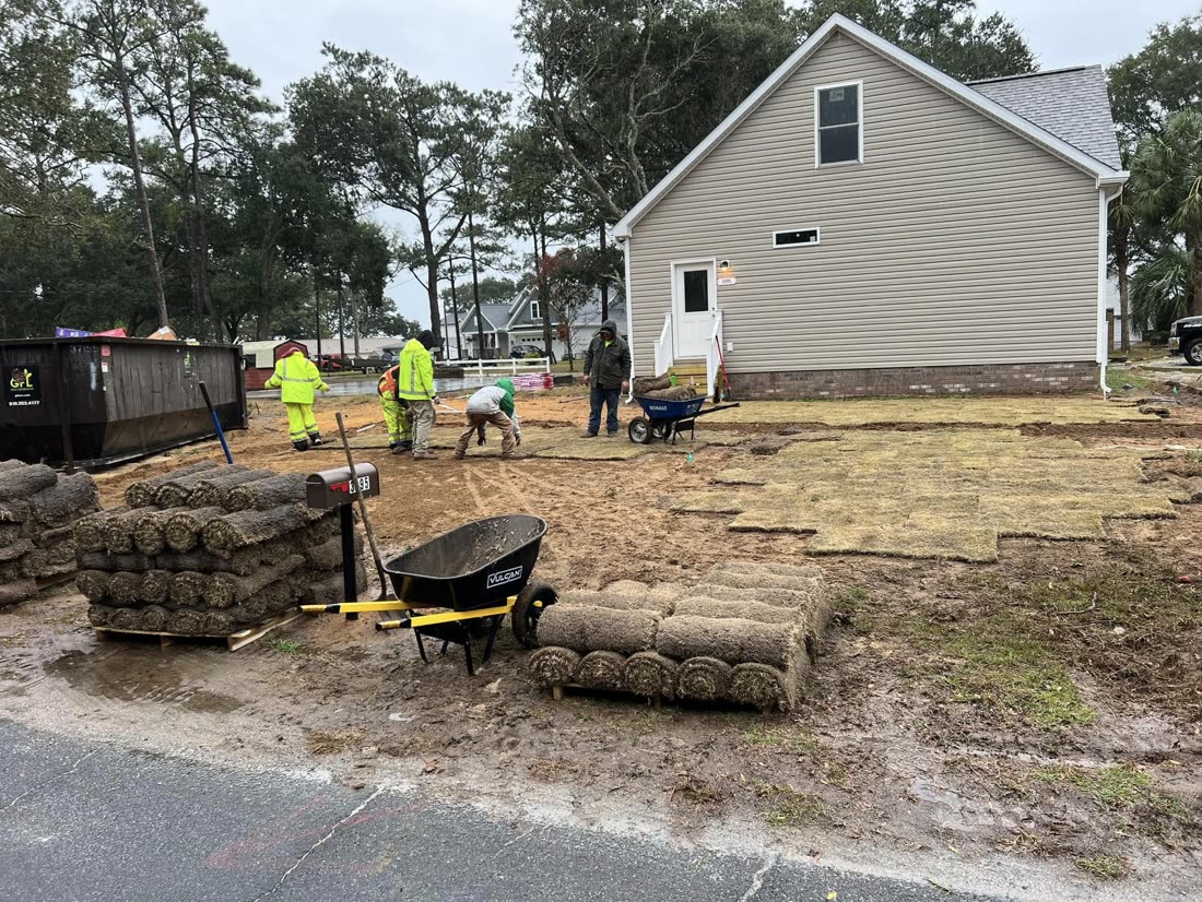 The crew laying sod from pallets behind a home