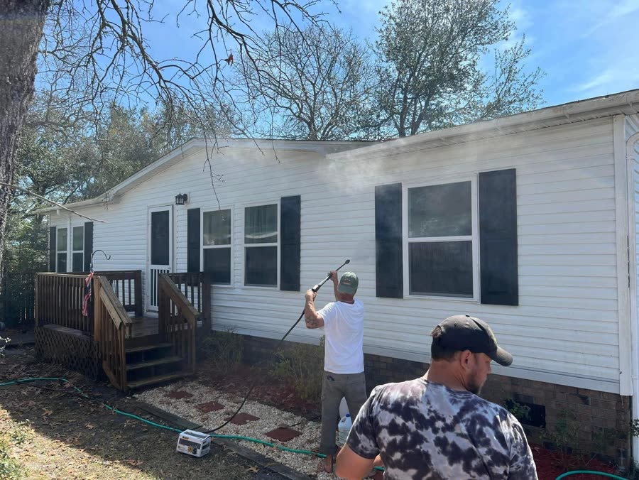 Pressure washing the siding of a white house