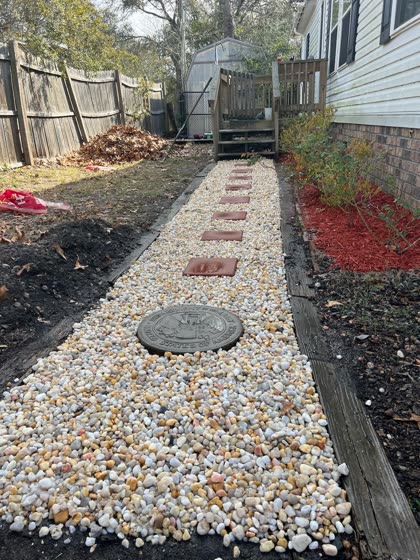 River rock path with stepping stones along a fence
