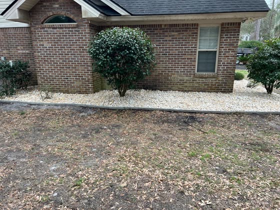 White river rock bed along the foundation of a brick home