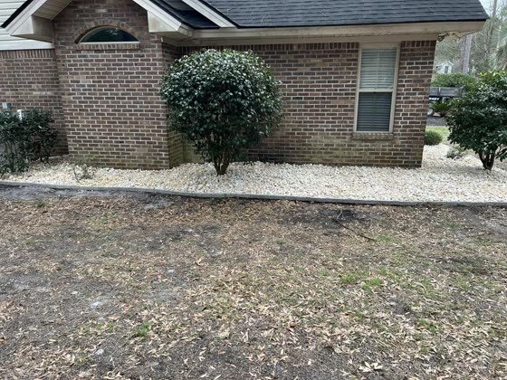 Rock bed and shrub at a brick home