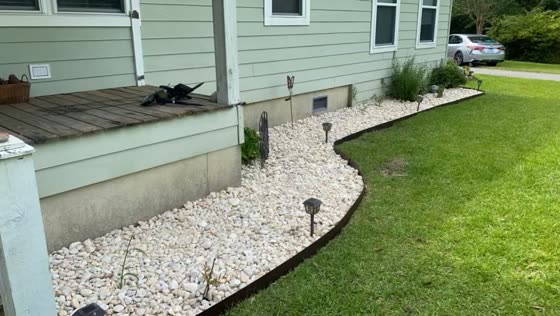 Curved white rock bed along a home